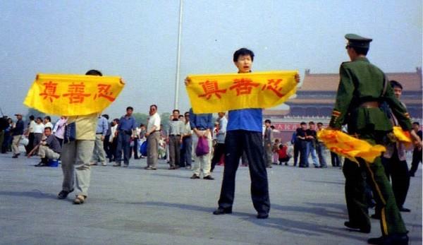 Un pratiquant de Falun Gong tient une banderole sur la place Tiananmen, sur laquelle on peut lire les caractères chinois « Vérité, Compassion, Tolérance », qui sont les principes fondamentaux de la pratique. Un policier s’approche pour l’arrêter.  (Image : Falun Dafa Information Center)